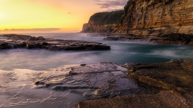 A rocky coastline with waves and cliffs at sunset.