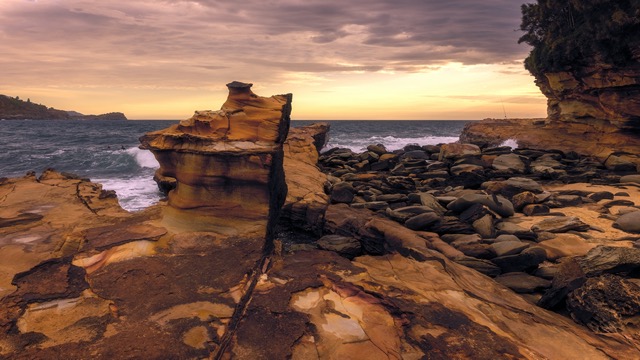 A rocky cliff overlooking the ocean at sunset.
