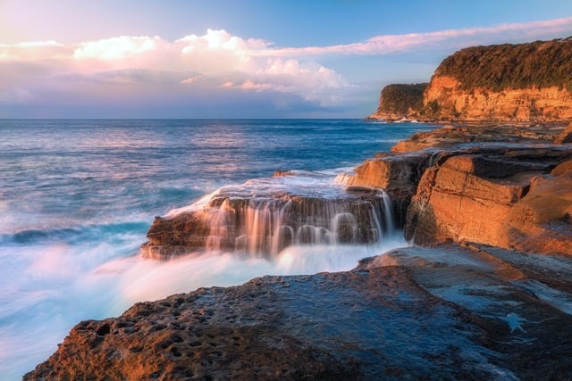 A rocky coastline with waves crashing over it.