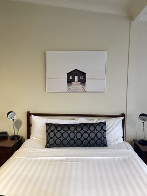 A solo traveler's bed with a painting on the wall.