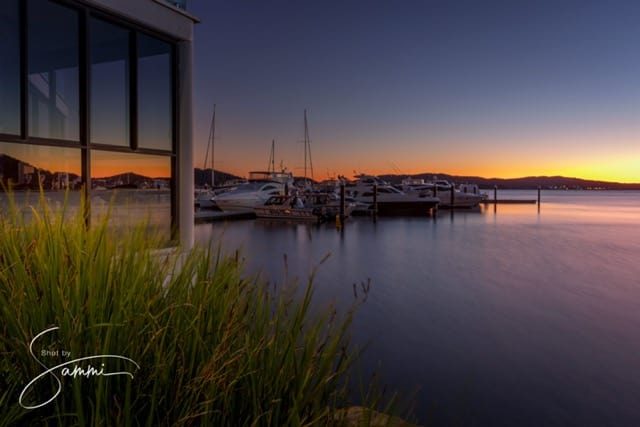 A sunset landscape photo with a boat docked in the water.
