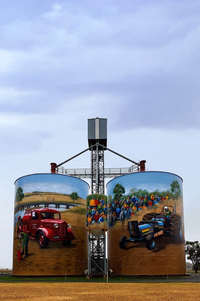 A silo painted with a car and truck.