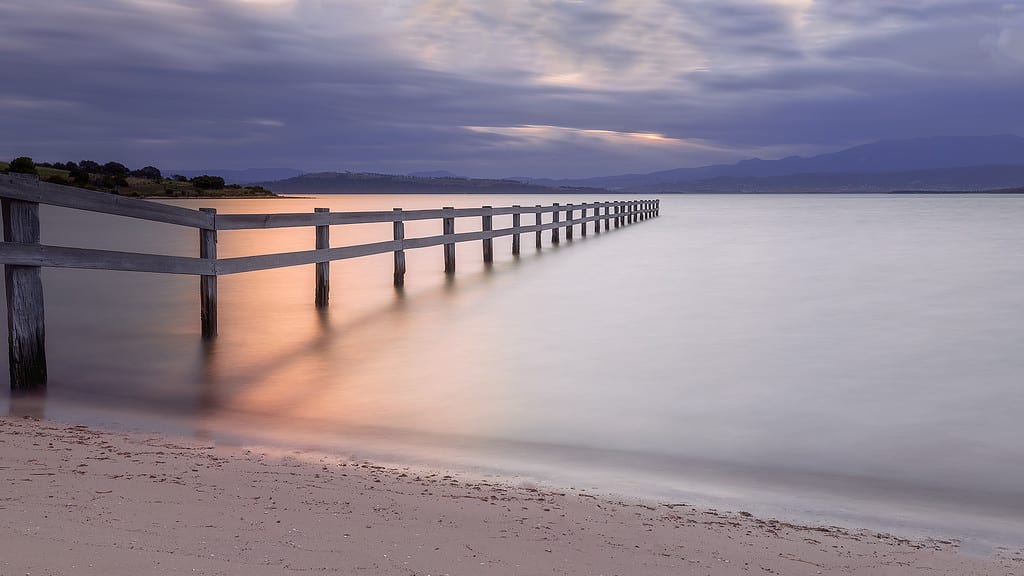 Using neutral density filters to slow down water movement - fence leading into a lake at sunset