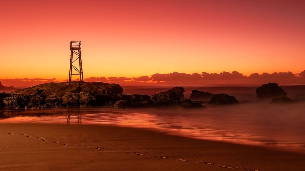 A lifeguard tower on a beach at sunset.