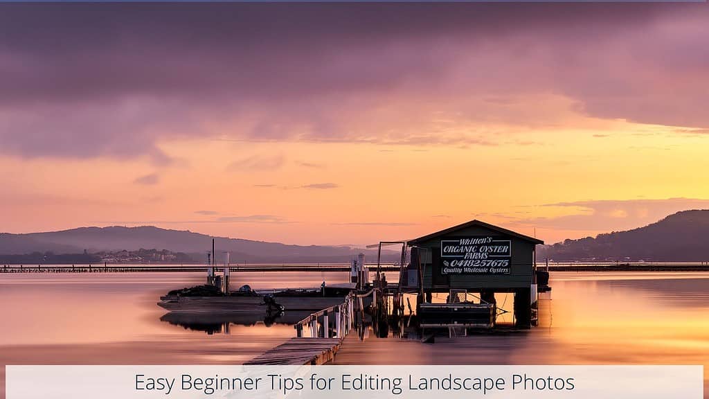 The image features a peaceful waterfront scene at sunset, with a floating oyster shed. The shed is anchored beside a small pier with boats moored nearby. The water reflects the stunning gradient of the sky, transitioning from purple to a warm golden hue, while the distant hills create a serene backdrop. The text "Easy Beginner Tips for Editing Landscape Photos" along the bottom
