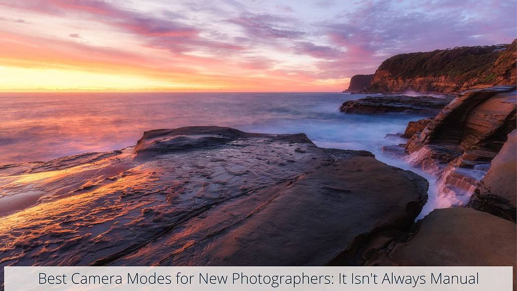 Rocky coastline with cascading water at sunset, under a sky painted with vibrant hues of pink and orange, titled 'Best Camera Modes for New Photographers: It Isn't Always Manual'. Background image location: Avoca Beach, NSW, Australia